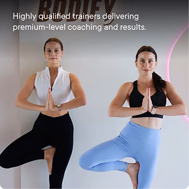 Two female fitness trainers demonstrating a yoga tree pose inside the BODIFY women-only fitness studio, showcasing professional coaching and a supportive training environment.