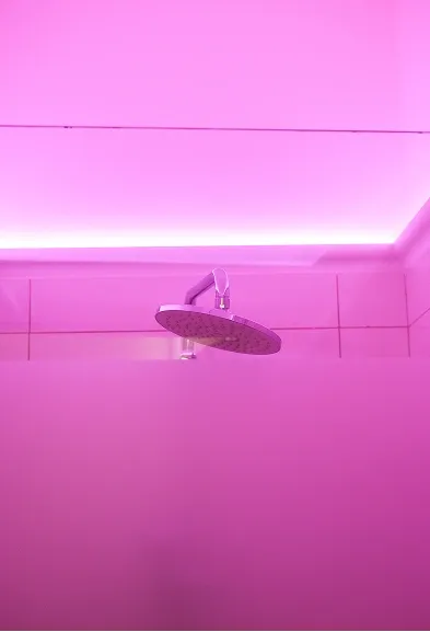 Rain shower head under pink ambient lighting in the stylish BODIFY changing area