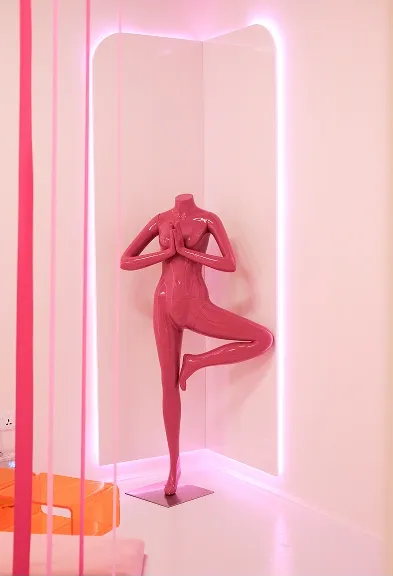 Pink headless yoga figure posed in tree position as part of the sculptural decor inside BODIFY