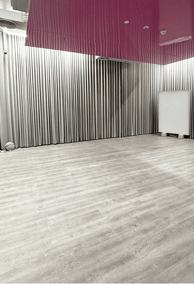 Spacious workout room with wooden floors and soft curtains at BODIFY