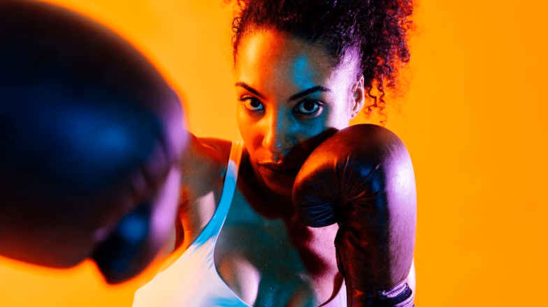 Woman in boxing gloves training intensely, representing a high calorie burning workout session