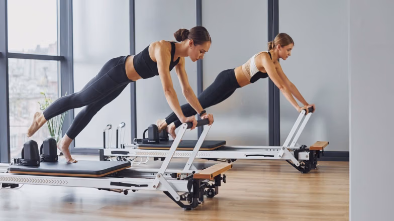 Woman performing a strength exercise on a reformer machine, combining resistance training and calorie burning