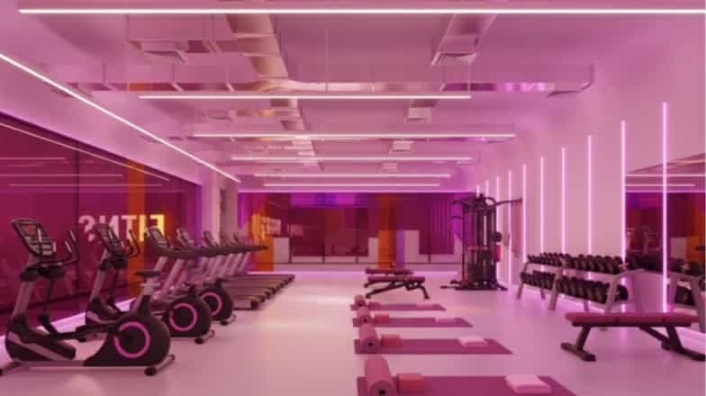 Spacious gym interior with cardio machines, free weights, and pink ambient lighting for a motivating workout environment