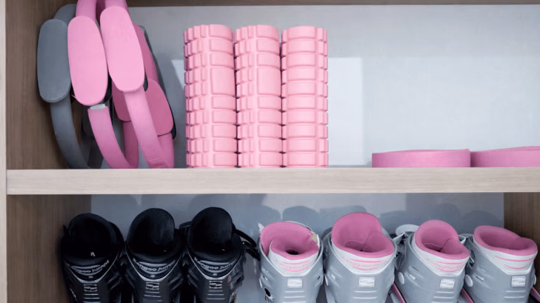 Shelves with neatly arranged yoga mats and foam rollers in a fitness studio