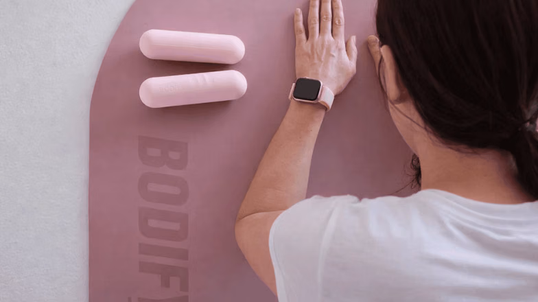 Woman rolling out a yoga mat in a modern studio, preparing for a stretching or fitness session