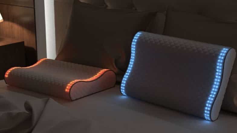 Two ergonomic support pillows with illuminated contours placed on a bed