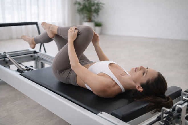 Woman doing a mobility exercise on a reformer during a deload week workout at a women-only studio in Dubai