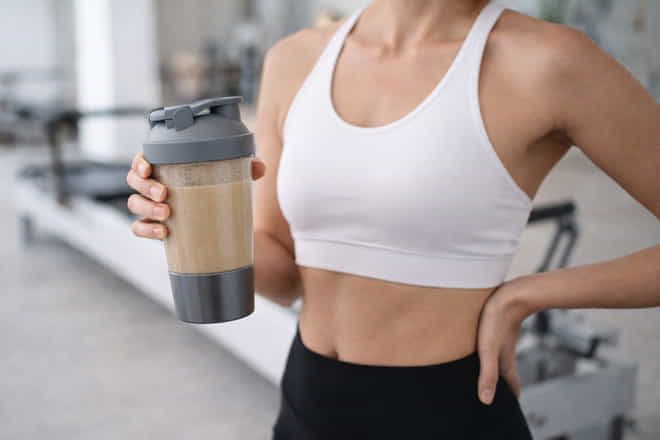 Woman holding a protein shake after a workout at a women-only fitness studio in Dubai