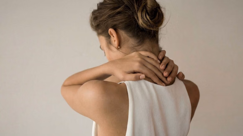 Woman holding her neck after a workout, highlighting the importance of rest and recovery between sets for muscle growth